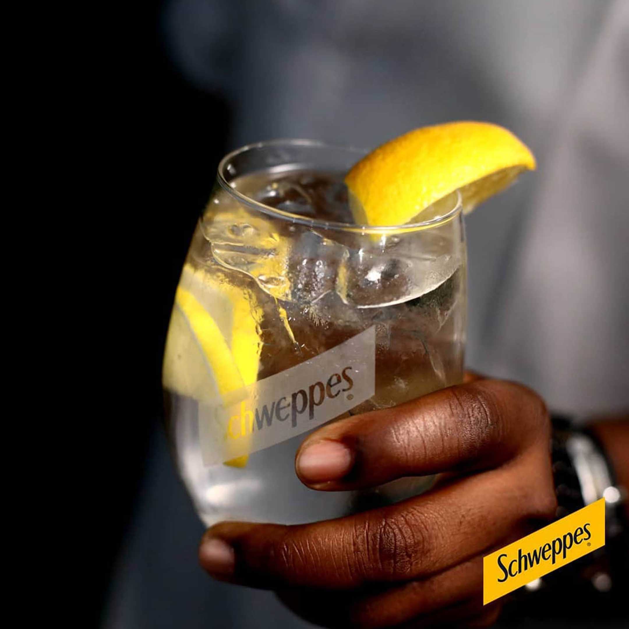 hand holding glass of Schweppes